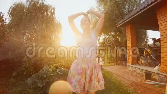 快乐的笑女在花园水管的水流下跳舞的慢镜头视频的预览图