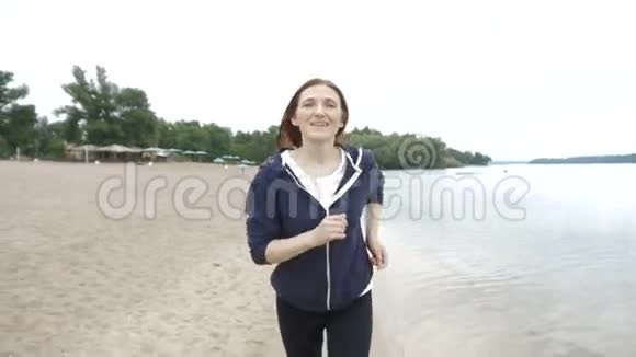 年轻健康的生活方式女人在日出海滩跑步在城市海滩附近的沙滩上奔跑的女孩视频的预览图
