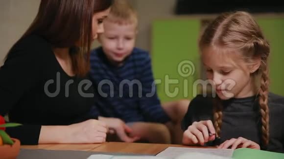 母女俩在做学校作业一个小男孩在看哥哥帮忙做作业视频的预览图