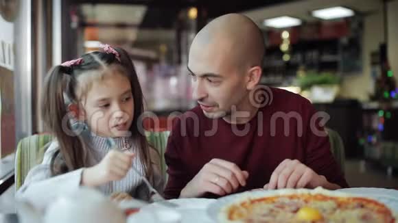 爸爸和一个小女儿在披萨店吃披萨视频的预览图