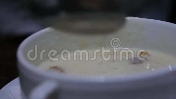 在一个碗里加奶酪汤女孩用勺子搅拌汤慢动作视频的预览图