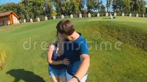 从摄像机拍摄的慢镜头拍摄的快乐年轻夫妇在公园接吻视频的预览图