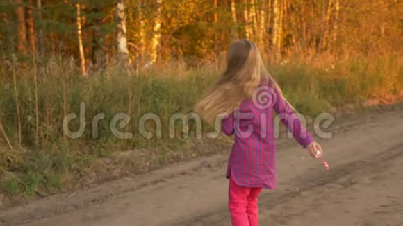 漂亮的女孩捕捉肥皂泡秋景林路金色的秋天慢速手持视频的预览图