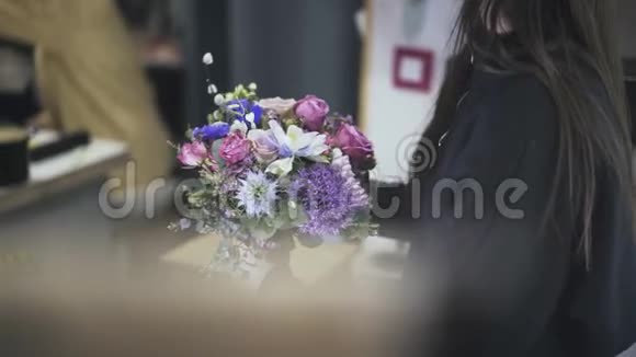 一位女花店师傅在一旁欣赏着一束美丽的鲜花视频的预览图