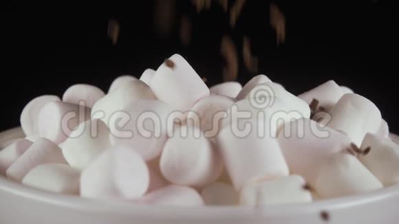棉花糖洒在黑色背景上的磨碎巧克力慢动作视频的预览图