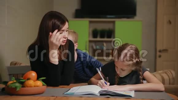 母女俩在做学校作业一个小男孩在看哥哥帮忙做作业视频的预览图
