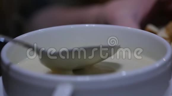 在一个碗里加奶酪汤女孩用勺子搅拌汤慢动作视频的预览图