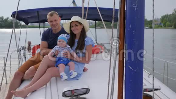 与宝宝在海上游艇上度假在湖上船上休息的幸福家庭画像家庭旅行视频的预览图
