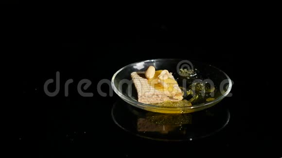 手把华夫饼和蜂蜜和坚果放在一个黑色背景的碗里视频的预览图