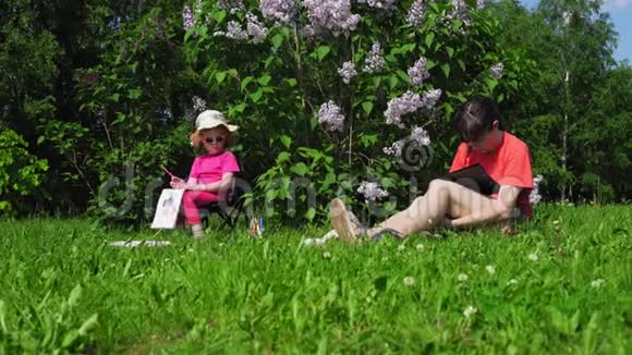 家庭母女在公园里开花的丁香灌木丛旁边画画视频的预览图