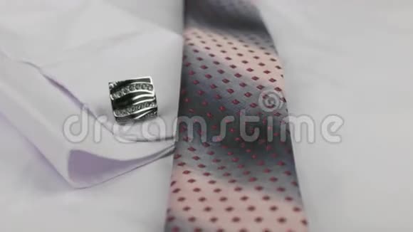 一条粉红色领带和袖扣的特写躺在白色衬衫上视频的预览图