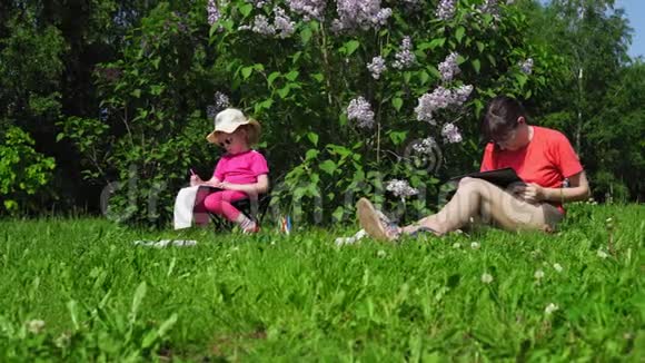 家庭母女在公园里开花的丁香灌木丛旁边画画视频的预览图