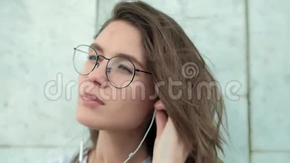 灰色大理石墙上戴着眼镜的美丽黑发女孩音乐悦耳她喜欢视频的预览图