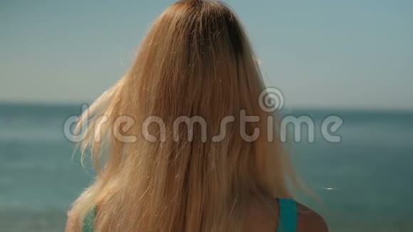 金发女人背对着海岸站着视频的预览图