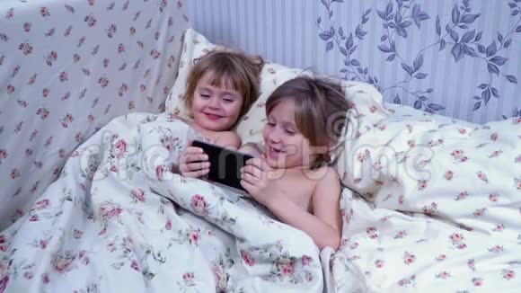 躺在毯子下的儿童使用智能手机视频的预览图