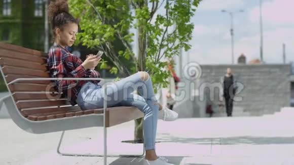 年轻可爱的女孩在城市里用手机发短信视频的预览图