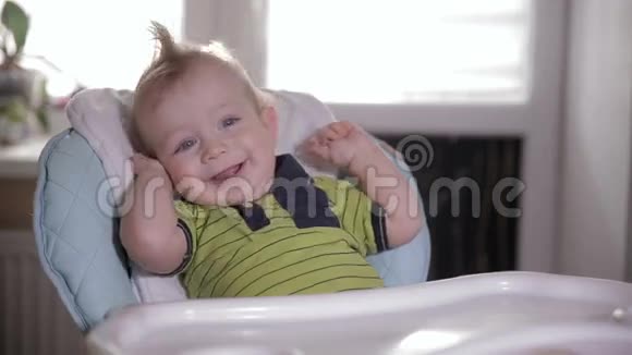 可爱的婴儿在厨房椅子上笑着伸展身体视频的预览图