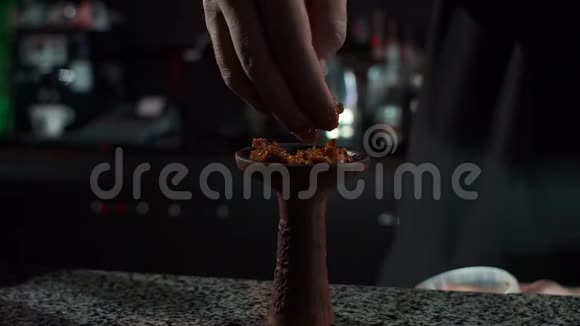 一个男人的特写把水果烟草放在碗里作为一个钩子在一个钩子酒吧视频的预览图