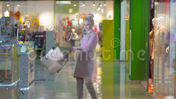 漂亮的女孩带着购物袋摆姿势在购物中心调情视频的预览图