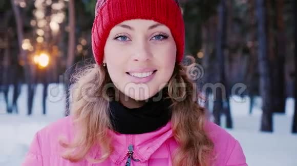 冬天森林里一个年轻迷人的白种人女人的肖像他正在夕阳的背景下对着镜头微笑视频的预览图
