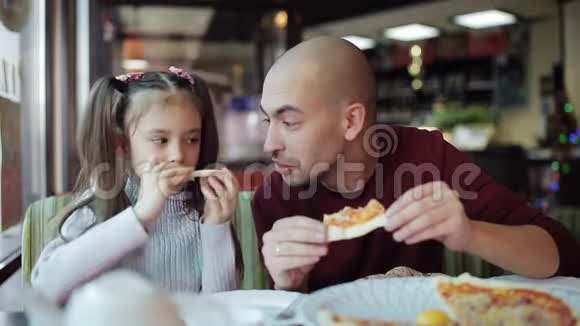 爸爸带着一个小女儿在披萨店里品尝香喷喷的披萨视频的预览图