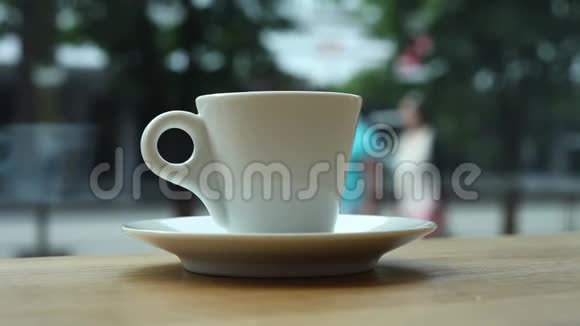 一杯咖啡放在一家咖啡馆的桌子上靠窗背景是人和汽车视频的预览图