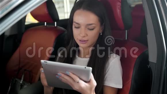 年轻漂亮的女人系好安全带坐在汽车后座上视频的预览图