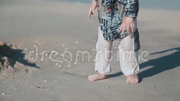 男孩年龄2岁外表漂亮在海边的沙滩上玩耍湿衣服和乐趣夏季一天视频的预览图