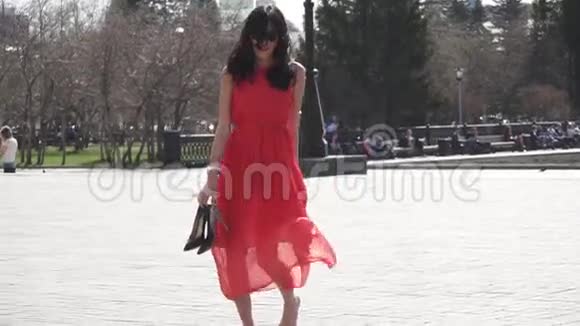 穿着红色衣服和太阳镜的女孩赤脚在城市里行走慢动作视频的预览图