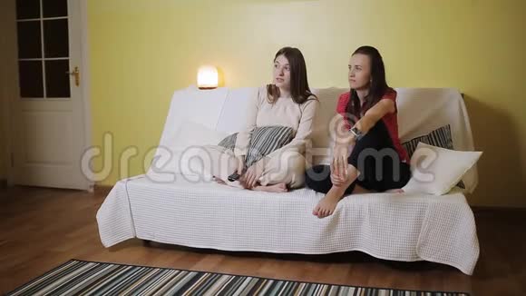 两个女朋友在家里一起在沙发上看电视视频的预览图