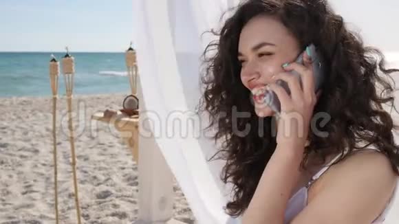 女人在堤岸上用手机聊天在热带岛屿上度暑假在海滩上打电话给女孩视频的预览图