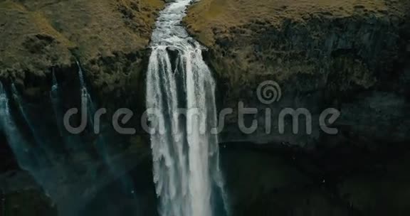 直升机在塞尔贾兰斯瀑布附近飞行湍急的水流从冰岛的山上流下来视频的预览图