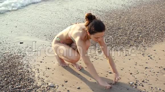 阳光明媚的一天年轻女子在海边的沙滩上心视频的预览图