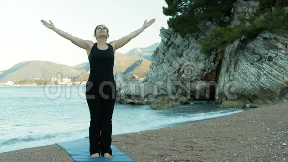 一位成年妇女在悬崖边的海边做瑜伽练习视频的预览图