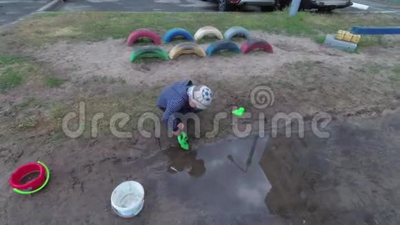 男孩从水坑里捡起水视频的预览图