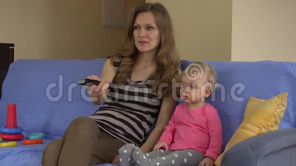 妈妈拿着遥控器女儿坐在沙发上看电视视频的预览图