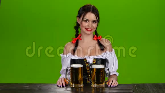 身着巴伐利亚服装的女士提供两杯啤酒绿色屏幕视频的预览图