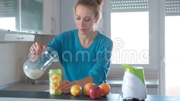 厨房里的女人用一个小搅拌器做水果冰沙视频的预览图