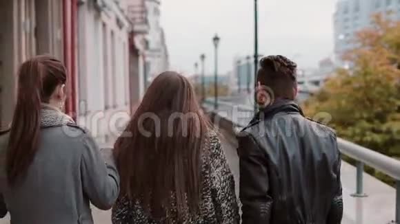 两个时髦的女孩和两个时髦的男人兴高采烈地在城市里散步和交谈慢影稳拍后景视频的预览图