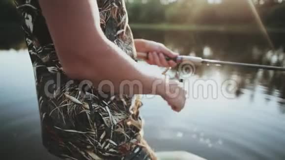 近景男性手拿鱼竿与旋转卷筒年轻人一个人钓鱼视频的预览图