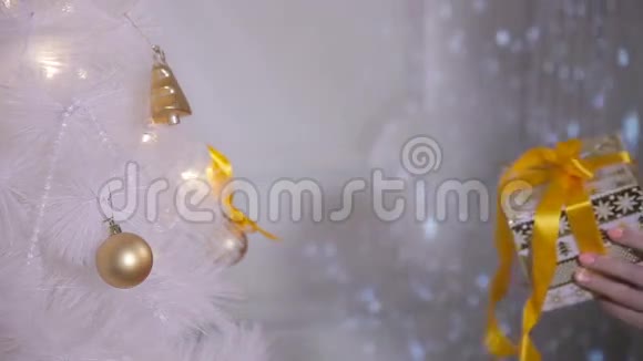 女人的手拿着圣诞树附近的礼物新年装饰快关门视频的预览图