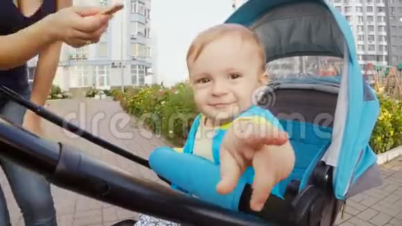 年轻的妈妈给坐在婴儿车里的小儿子送饼干视频的预览图