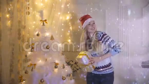 幸福微笑的年轻女子带着礼物在圣诞树旁跳舞新年除夕圣诞节的概念视频的预览图