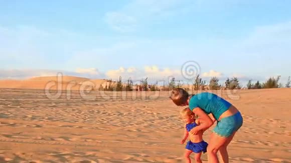 在日落时分妈妈和小女孩一起在沙丘上奔跑视频的预览图