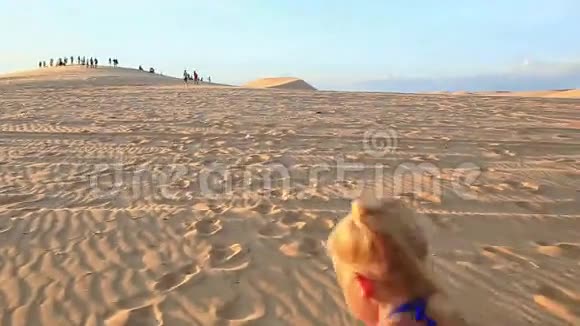 小女孩光着脚走在沙丘上日落时累了视频的预览图