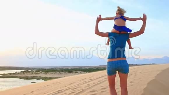 母亲骑着小女孩骑着肩膀在沙丘上转视频的预览图