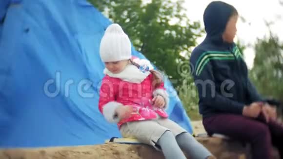 一个幸福美丽的家庭坐在旅游帐篷附近的海滩上视频的预览图