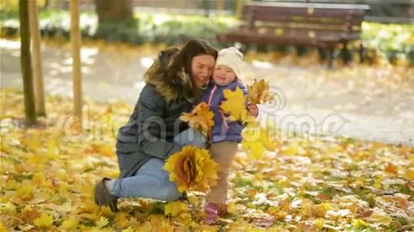 幸福的家庭母子小女儿在大自然中嬉戏抱着树叶笑着拥抱秋天视频的预览图