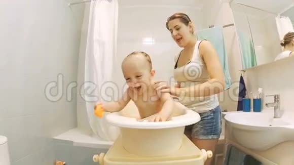 可爱活泼的小男孩和年轻微笑的妈妈一起洗澡视频的预览图
