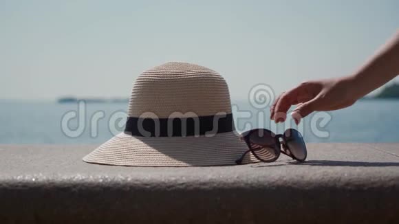 女性手轮流从框架中取出太阳镜和草帽海景视频的预览图